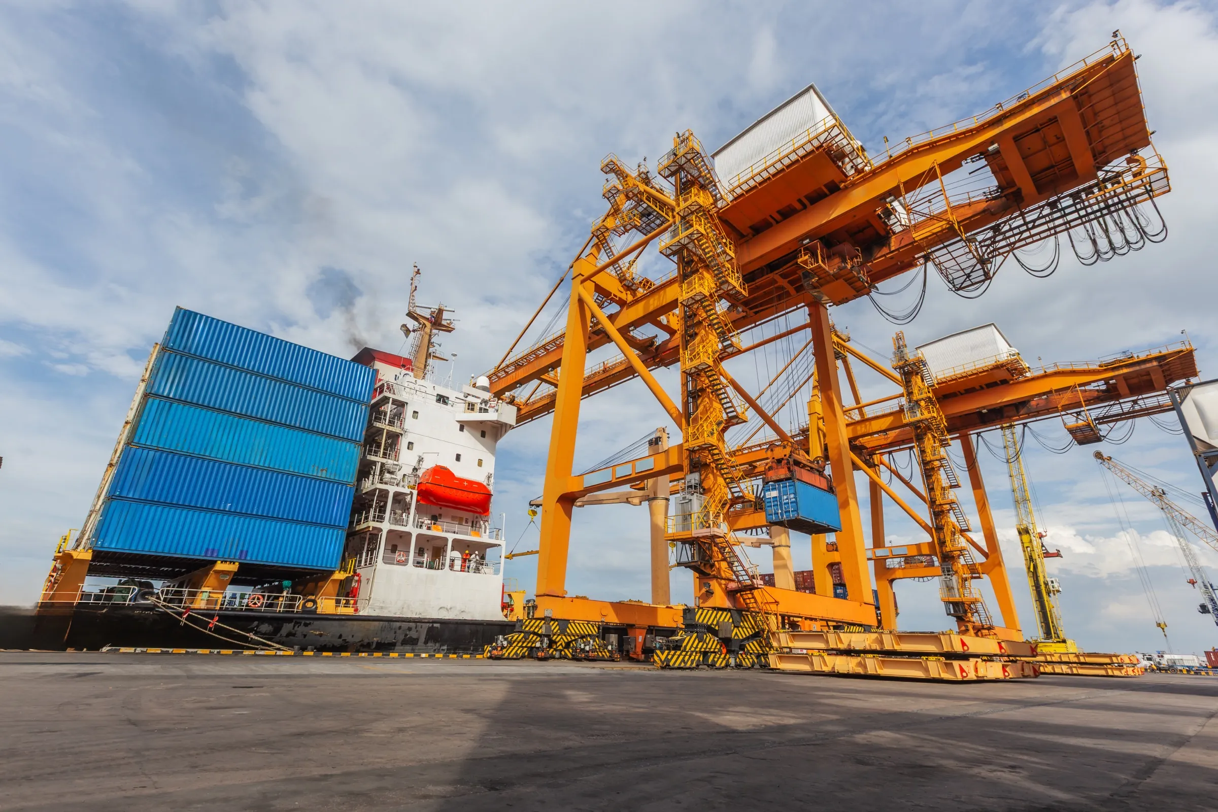 Massive yellow gantry cranes standing beside a cargo ship at a container terminal